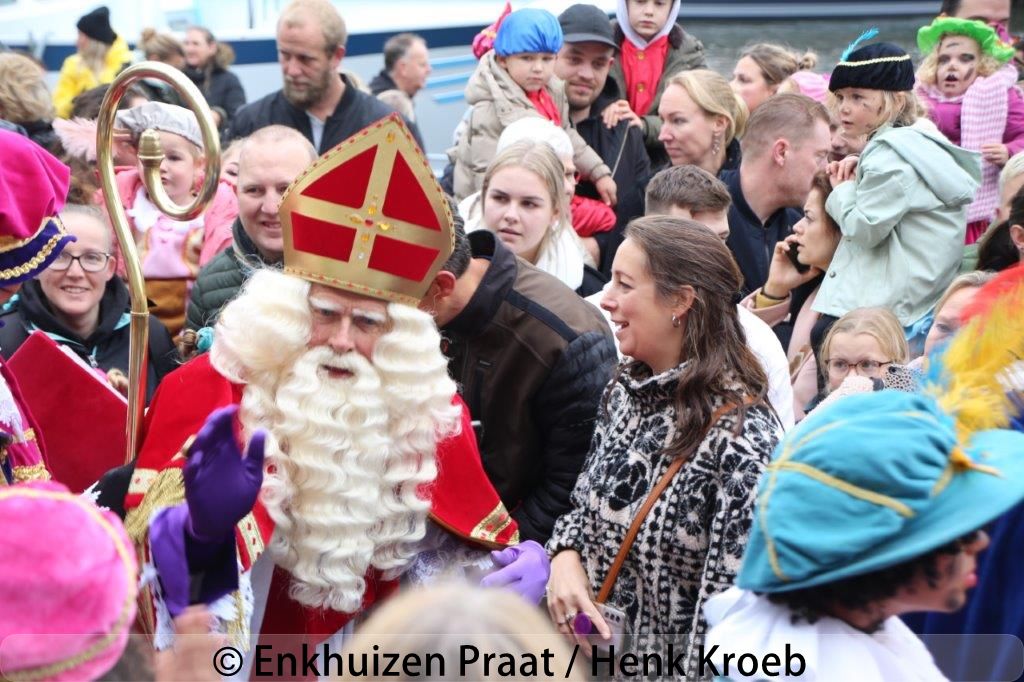Sinterklaas arriveert in de Oude Haven van Enkhuizen tijdens de intocht van 2025, omringd door Pieten en feestende kinderen.