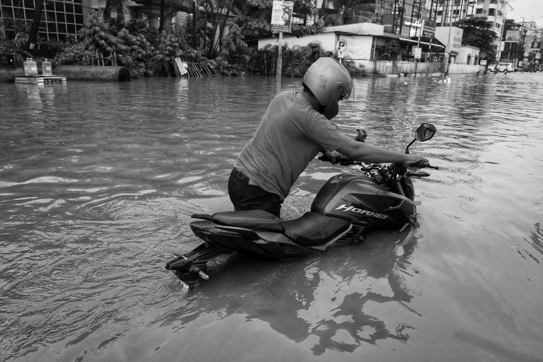 man dragging a motorcycle through the flooding