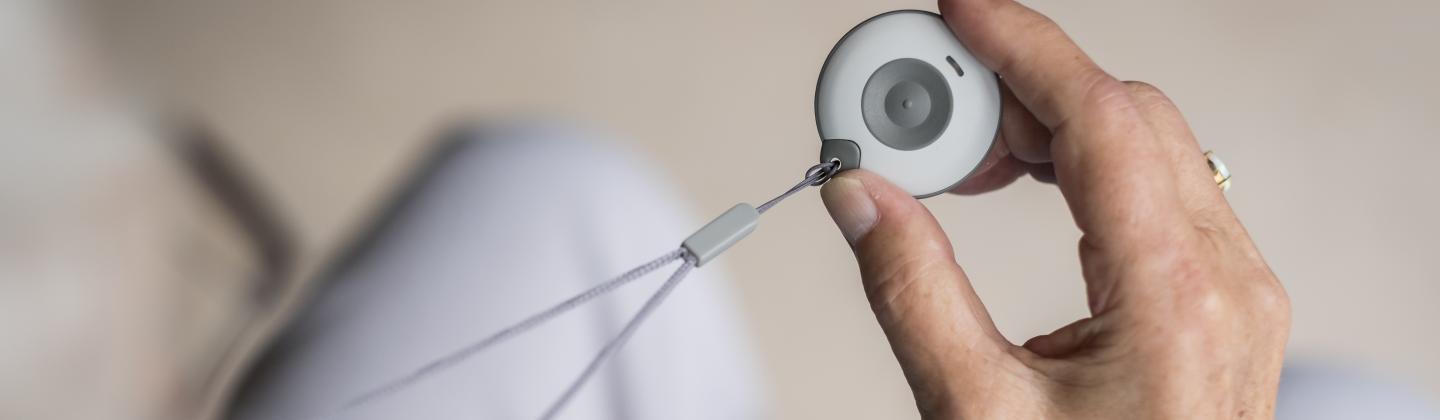 Een zorgprofessional draagt een alarmknop op haar uniform tijdens haar werk in een zorginstelling.