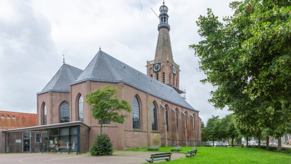 De monumentale Bonifaciuskerk in Medemblik bij zonsondergang, waar inwoners worden uitgenodigd om mee te denken over de toekomst van het gebouw.