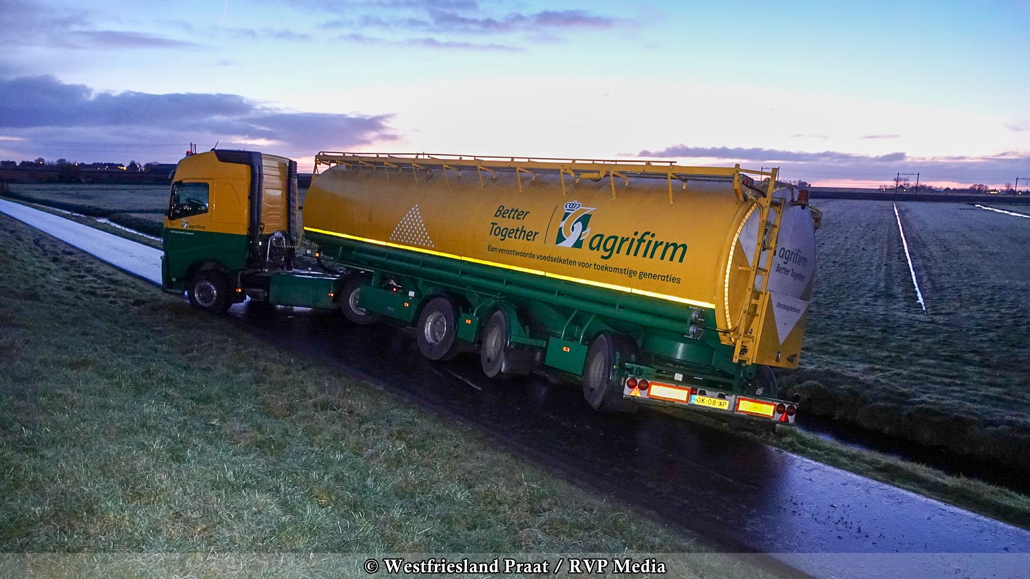 Vrachtwagen die op een gladde dijk in Schardam dreigt om te vallen naast een sloot.