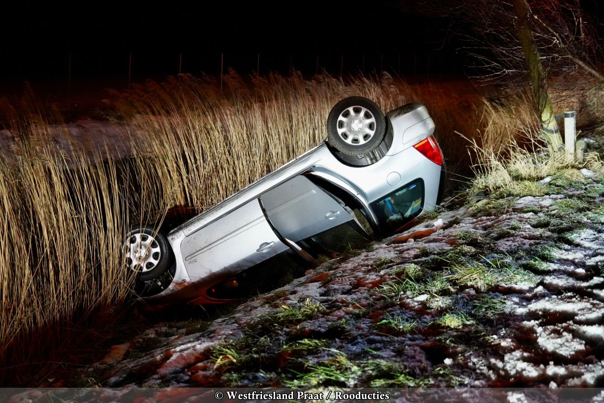 Verkeersongeval in Andijk waarbij een auto op het dak in het riet tot stilstand kwam