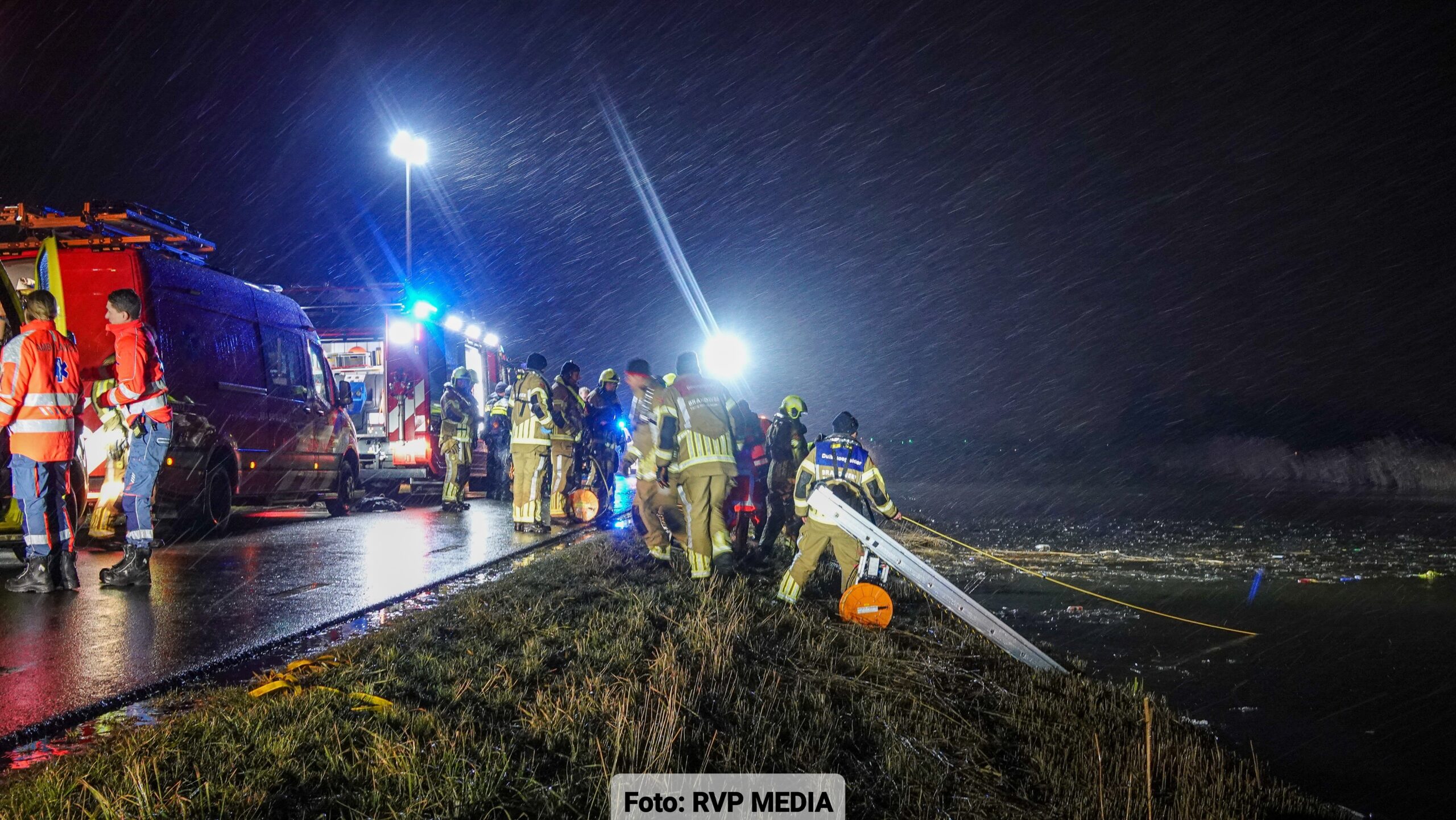 Hulpdiensten bij de ringvaart langs de Oostdijk in Heerhugowaard na een auto te water