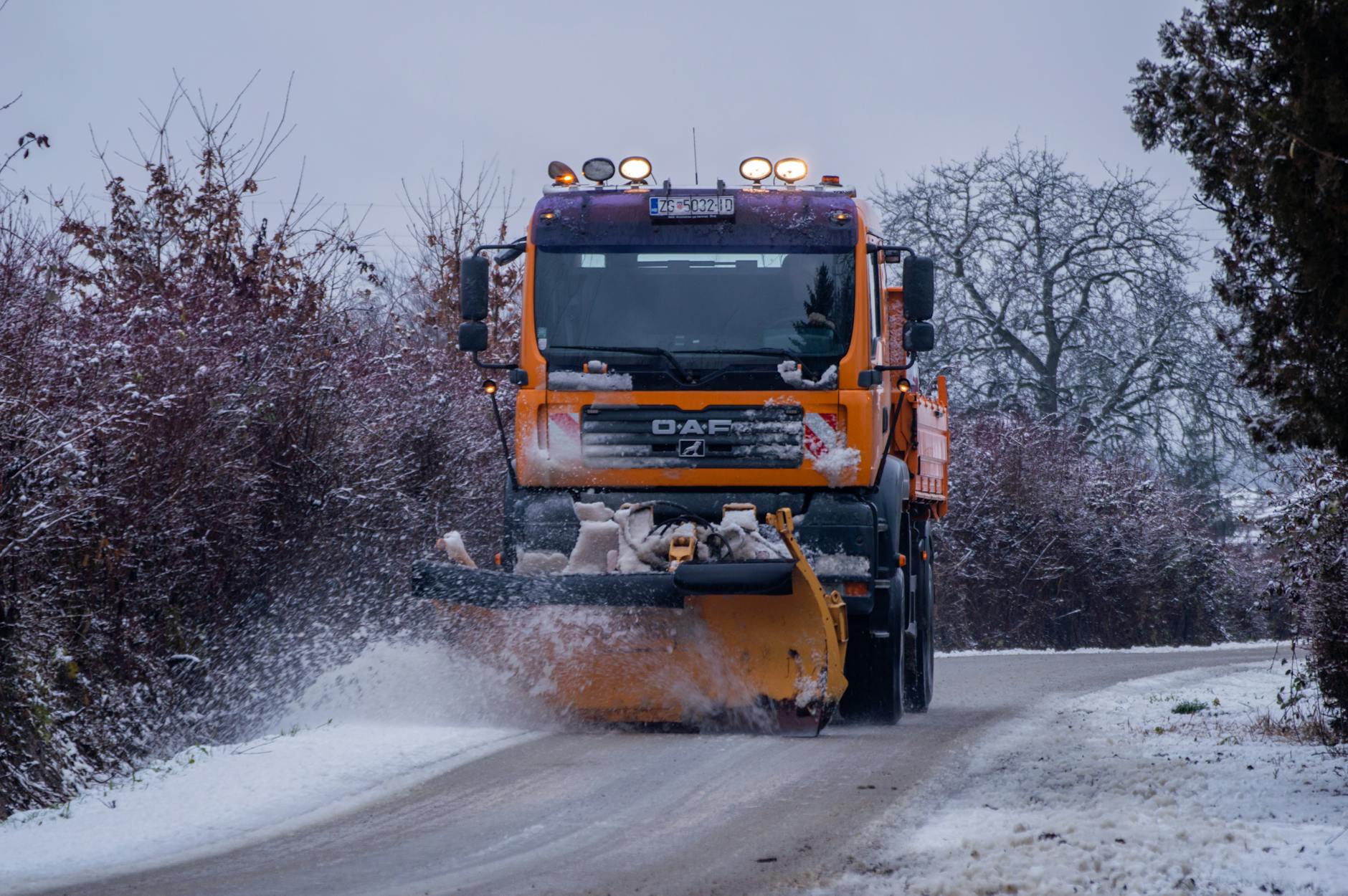 Strooivoertuig van de gemeente Opmeer strooit zout op een gladde weg tijdens winterse omstandigheden