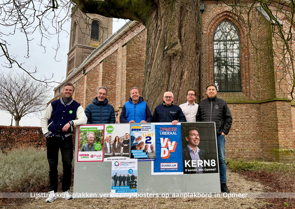 Lijsttrekkers plakken verkiezingsposters op aanplakbord in Opmeer
