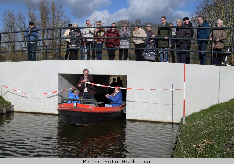 Wethouder Slagter opent vanaf een polderschuit de nieuwe vaarduiker aan de Parklaan in Lutjebroek.