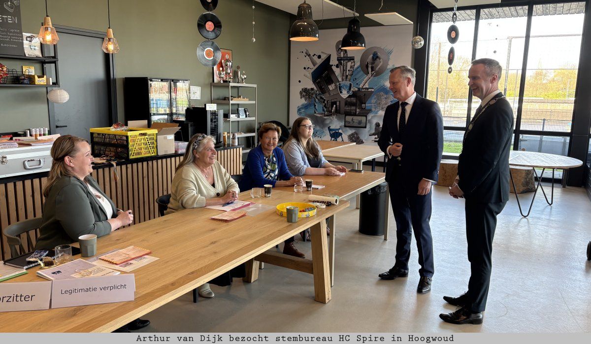 Commissaris van de Koning Arthur van Dijk bezoekt stembureau HC Spire in Hoogwoud en overhandigt appeltaart aan stembureauleden.