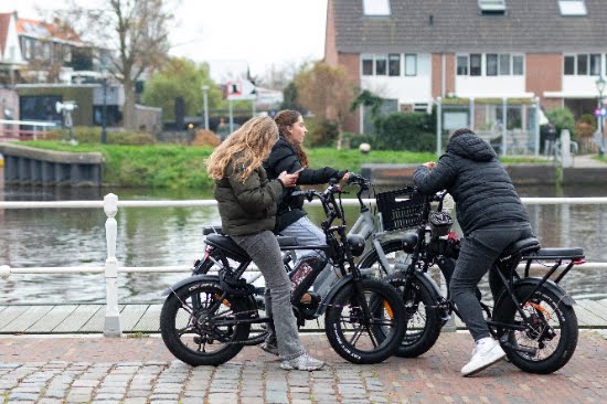 Jonge bestuurders op fatbikes rijden door een drukke straat, wat zorgen oproept over verkeersveiligheid.