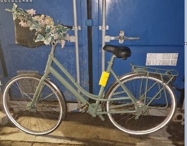 Lichtgroene damesfiets met bloemenslinger aan het stuur in de Nieuwstraat in Medemblik